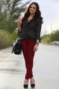 A woman showing how to match burgundy-colored pants with a black top and black shoes