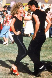 Oliva Newtown John and John Travolta in the movie "Grease". Oliva is donning shiny black leggings that became popular back then.